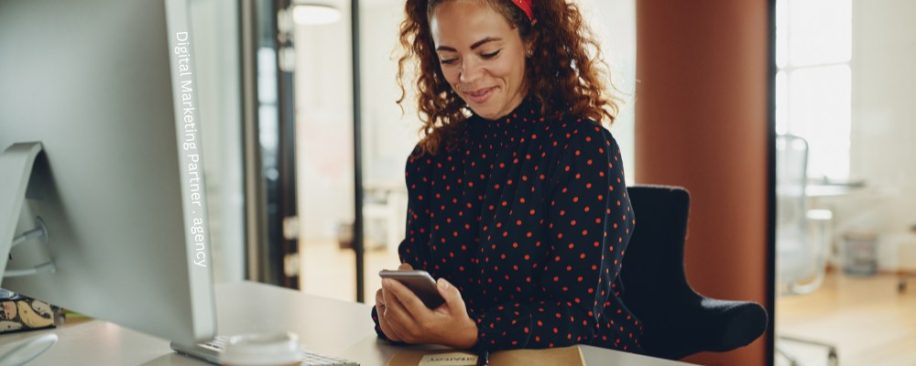 Image of a woman at a desk texting on your smartphone for business.