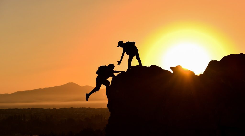 Image of hikers climbing with orange sunset in background