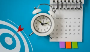 Old-fashioned alarm clock on a calendar with a blue background.